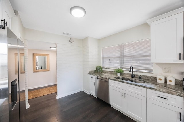 kitchen featuring appliances with stainless steel finishes, sink, dark stone countertops, white cabinets, and dark wood-type flooring