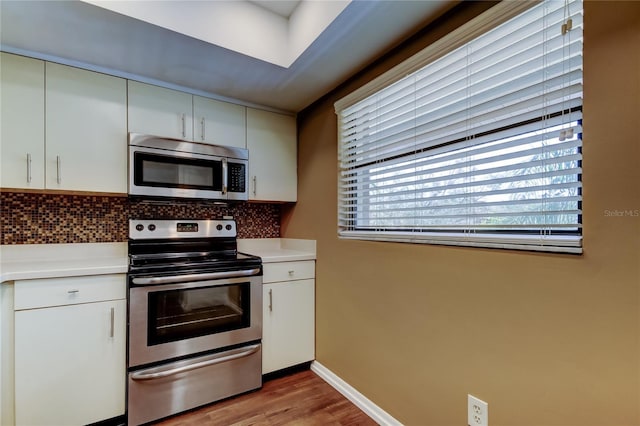 kitchen with appliances with stainless steel finishes, light wood-type flooring, decorative backsplash, and white cabinets