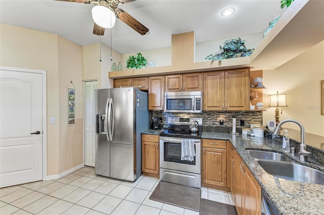 kitchen featuring sink, light tile patterned floors, dark stone countertops, backsplash, and stainless steel appliances