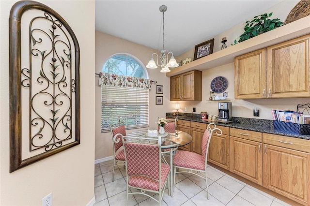 kitchen featuring an inviting chandelier, light tile patterned floors, decorative light fixtures, and dark stone counters