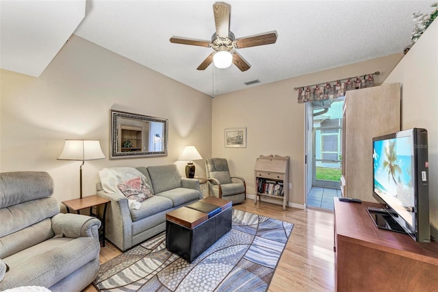 living room featuring vaulted ceiling, a textured ceiling, ceiling fan, and light hardwood / wood-style flooring