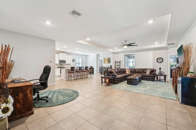 living room featuring light tile patterned floors, a tray ceiling, visible vents, and recessed lighting