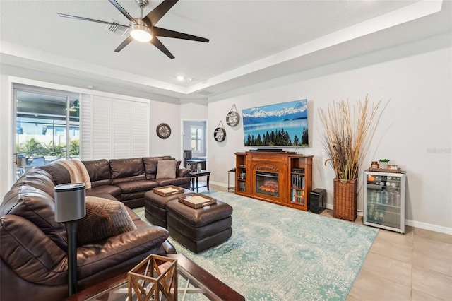 tiled living room with a tray ceiling, ceiling fan, and wine cooler