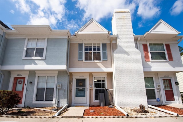 multi unit property featuring brick siding, a chimney, and stucco siding