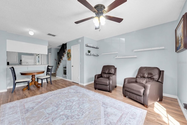 sitting room with baseboards, visible vents, stairway, wood finished floors, and a textured ceiling