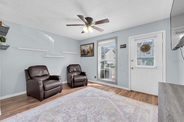 sitting room featuring hardwood / wood-style flooring, ceiling fan, and a textured ceiling