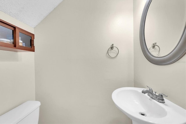 bathroom featuring sink, toilet, and a textured ceiling