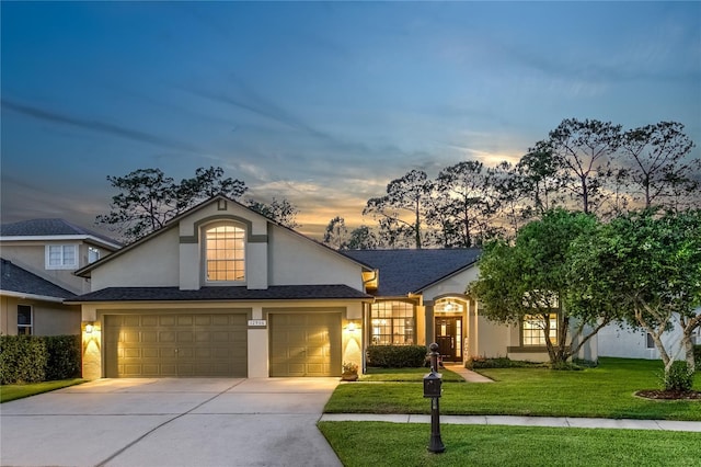 traditional-style home featuring stucco siding, concrete driveway, a yard, and an attached garage