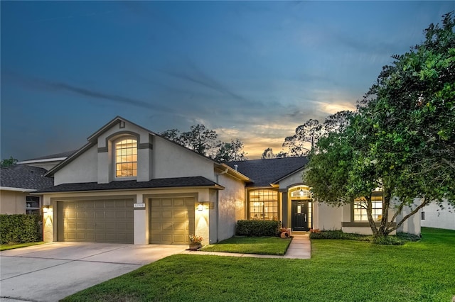 view of front facade with stucco siding, concrete driveway, a front yard, and an attached garage
