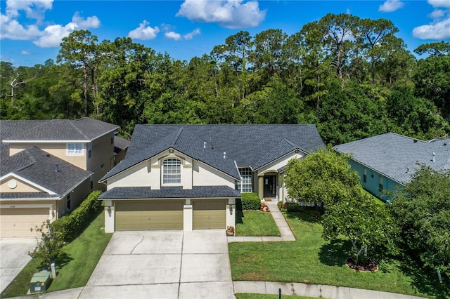 view of front facade featuring driveway, a front lawn, stucco siding, and roof with shingles