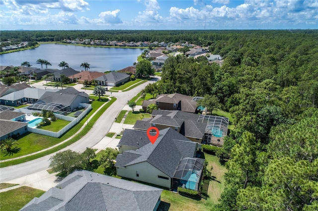 aerial view of residential area featuring a heavily wooded area and a nearby body of water