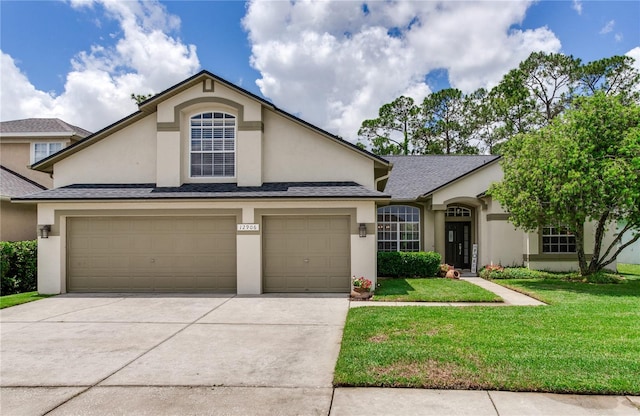 traditional home with stucco siding, a front yard, concrete driveway, and roof with shingles