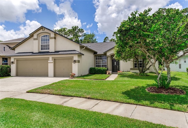 view of front facade featuring stucco siding, driveway, a front yard, and roof with shingles