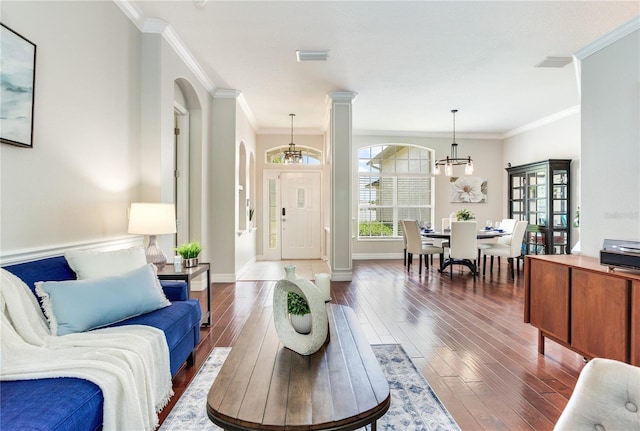 living area with arched walkways, wood-type flooring, crown molding, a chandelier, and baseboards