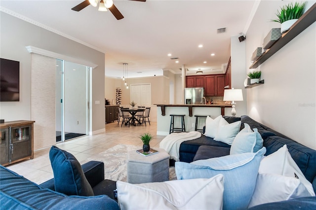 living room with light tile patterned floors, ceiling fan, ornamental molding, recessed lighting, and baseboards
