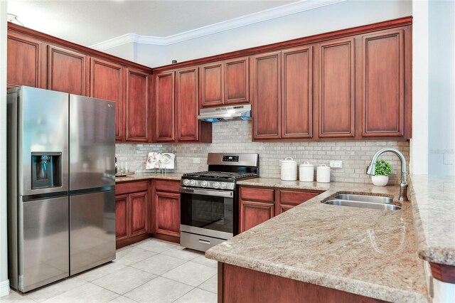 kitchen featuring stainless steel appliances, a sink, under cabinet range hood, light stone counters, and ornamental molding
