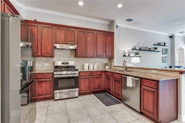 kitchen featuring appliances with stainless steel finishes, a sink, under cabinet range hood, a peninsula, and reddish brown cabinets