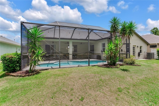 rear view of property featuring a ceiling fan, a lawn, glass enclosure, and central air condition unit