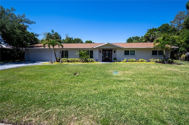 single story home with a garage, a front yard, driveway, and stucco siding