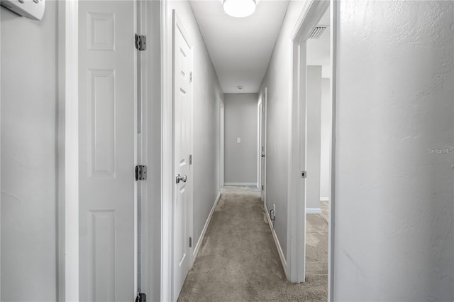 hall featuring an AC wall unit, light colored carpet, and baseboards