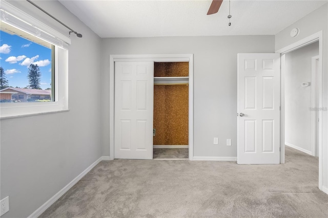 unfurnished bedroom with a ceiling fan, a closet, light colored carpet, and baseboards