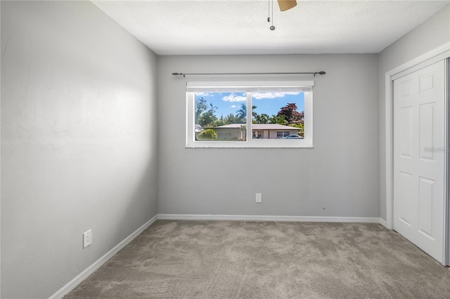 unfurnished bedroom with a ceiling fan, baseboards, a textured ceiling, and light colored carpet