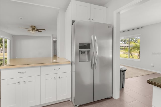 kitchen featuring plenty of natural light, stainless steel refrigerator with ice dispenser, a ceiling fan, and white cabinets