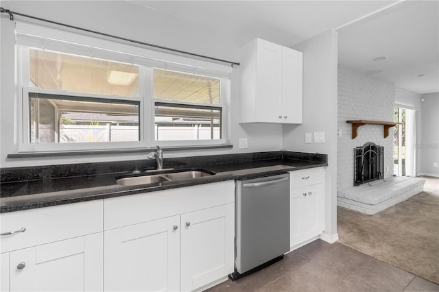 kitchen featuring a sink, white cabinets, stainless steel dishwasher, a brick fireplace, and dark carpet