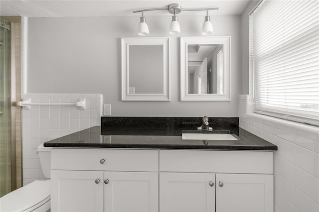 full bathroom with toilet, a wainscoted wall, vanity, and tile walls