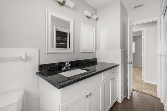 half bath with tile walls, visible vents, toilet, vanity, and tile patterned flooring