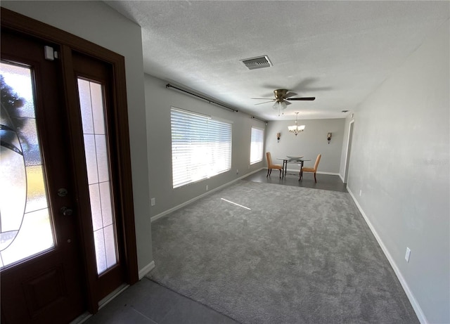 interior space with a textured ceiling, a notable chandelier, carpet floors, visible vents, and baseboards