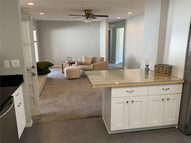 kitchen featuring dishwasher, open floor plan, light countertops, dark colored carpet, and white cabinetry