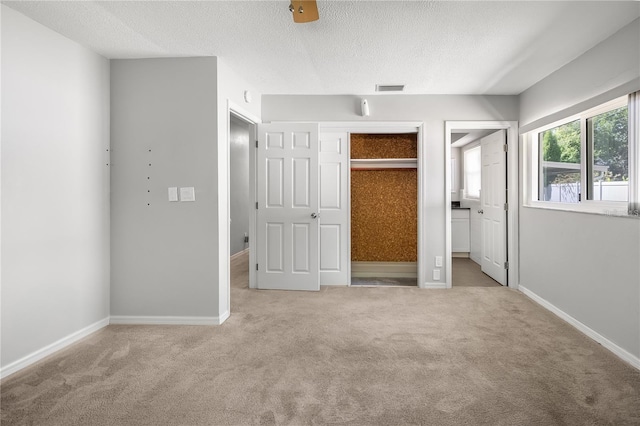 unfurnished bedroom featuring baseboards, light carpet, visible vents, and a textured ceiling