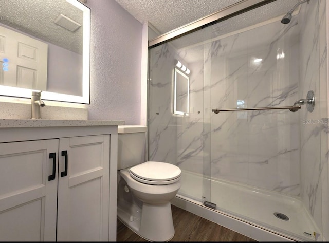 bathroom with hardwood / wood-style floors, vanity, an enclosed shower, a textured ceiling, and toilet