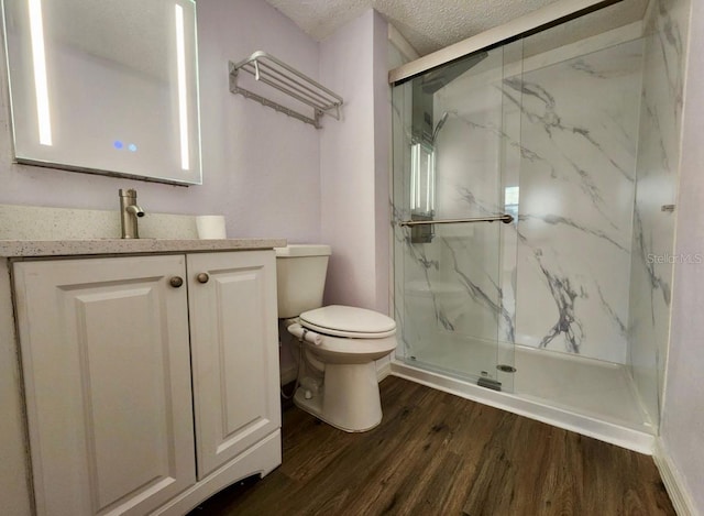 bathroom with hardwood / wood-style flooring, toilet, walk in shower, and a textured ceiling