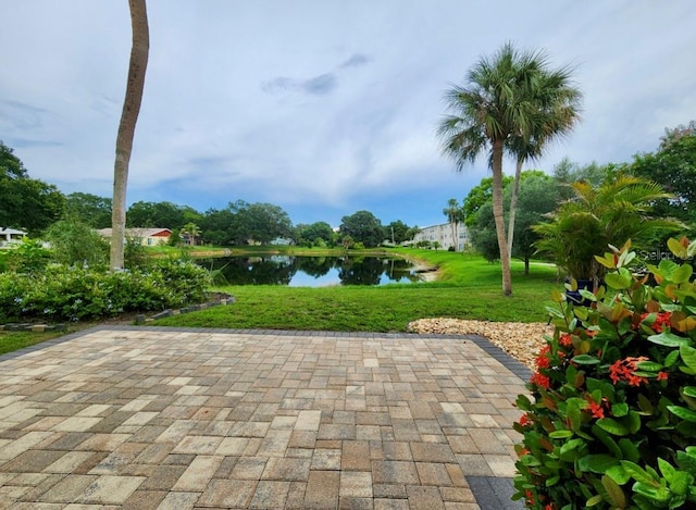 view of community featuring a water view, a yard, and a patio area