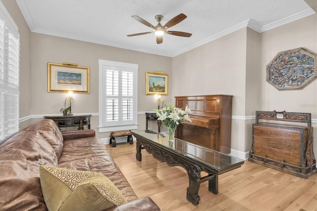 living area featuring baseboards, crown molding, light wood finished floors, and ceiling fan