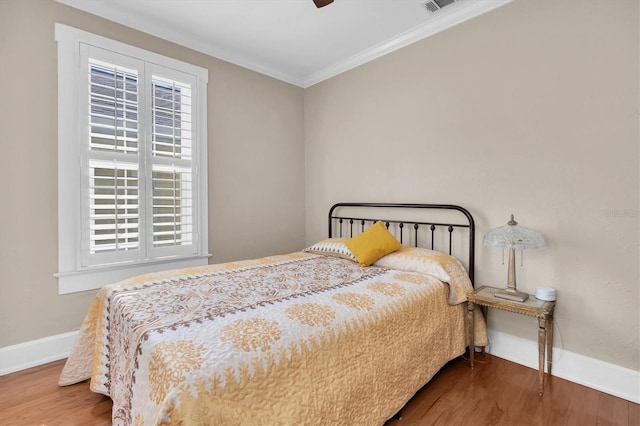 bedroom featuring multiple windows, ornamental molding, and wood finished floors