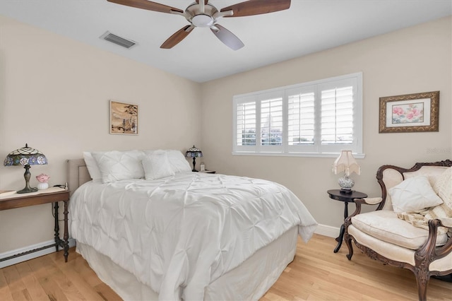 bedroom with light wood finished floors, visible vents, a baseboard heating unit, ceiling fan, and baseboards