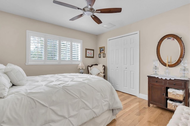 bedroom with light wood-type flooring, ceiling fan, visible vents, and a closet