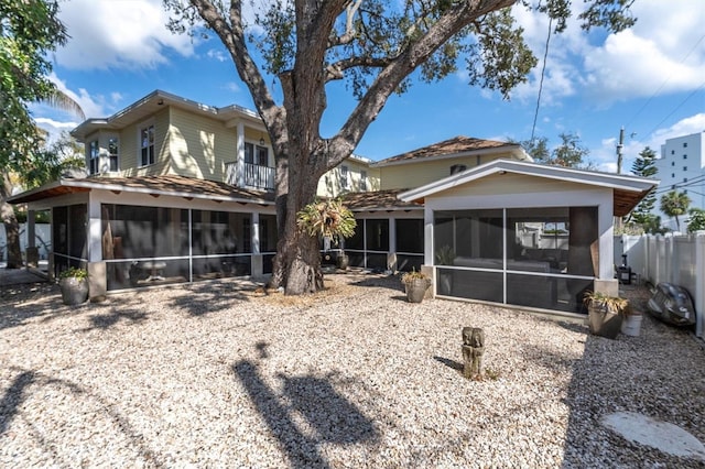 rear view of house featuring fence and a sunroom