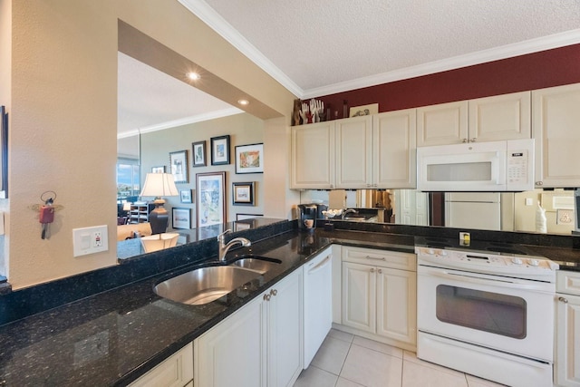 kitchen with a peninsula, white appliances, a sink, dark stone countertops, and crown molding