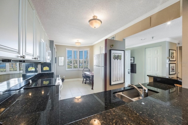 kitchen with ornamental molding, white appliances, white cabinets, and a sink