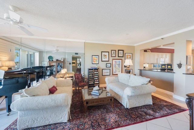 living area featuring crown molding, a ceiling fan, a textured ceiling, tile patterned flooring, and baseboards