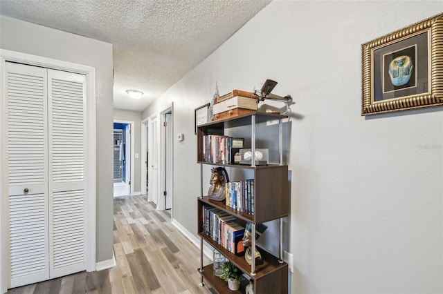 corridor with wood-type flooring and a textured ceiling