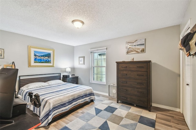 bedroom featuring light hardwood / wood-style flooring and a textured ceiling