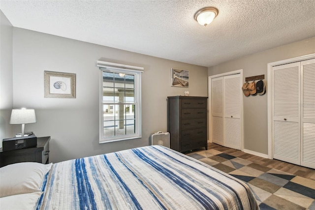 bedroom with multiple closets, dark hardwood / wood-style floors, and a textured ceiling