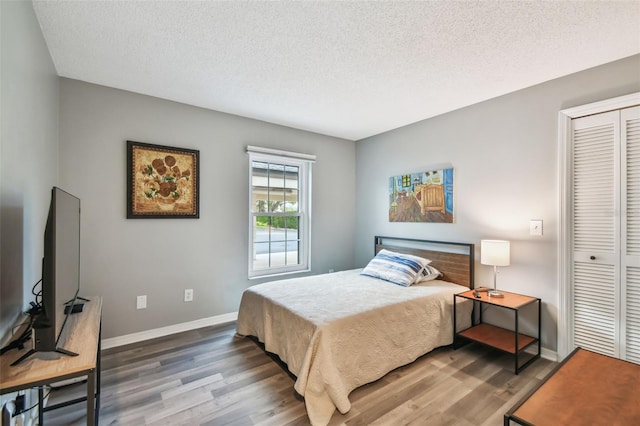 bedroom featuring dark hardwood / wood-style flooring, a closet, and a textured ceiling