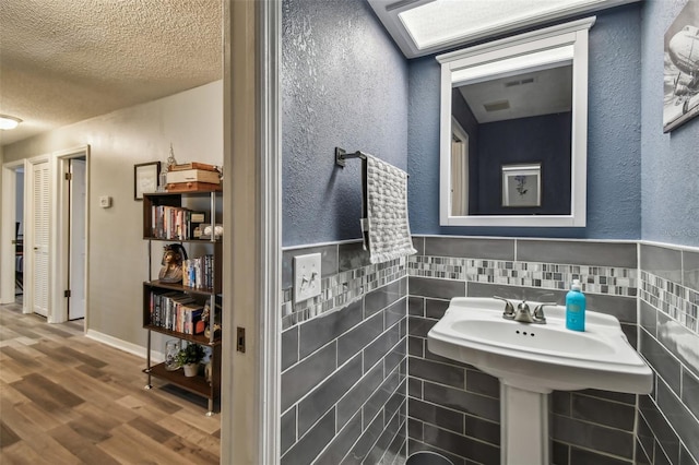 bathroom featuring tile walls, hardwood / wood-style flooring, and a textured ceiling