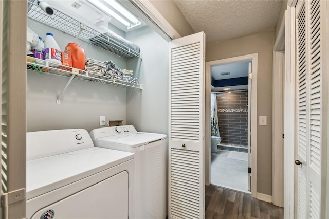 laundry area with dark wood-type flooring, washer and dryer, and a textured ceiling